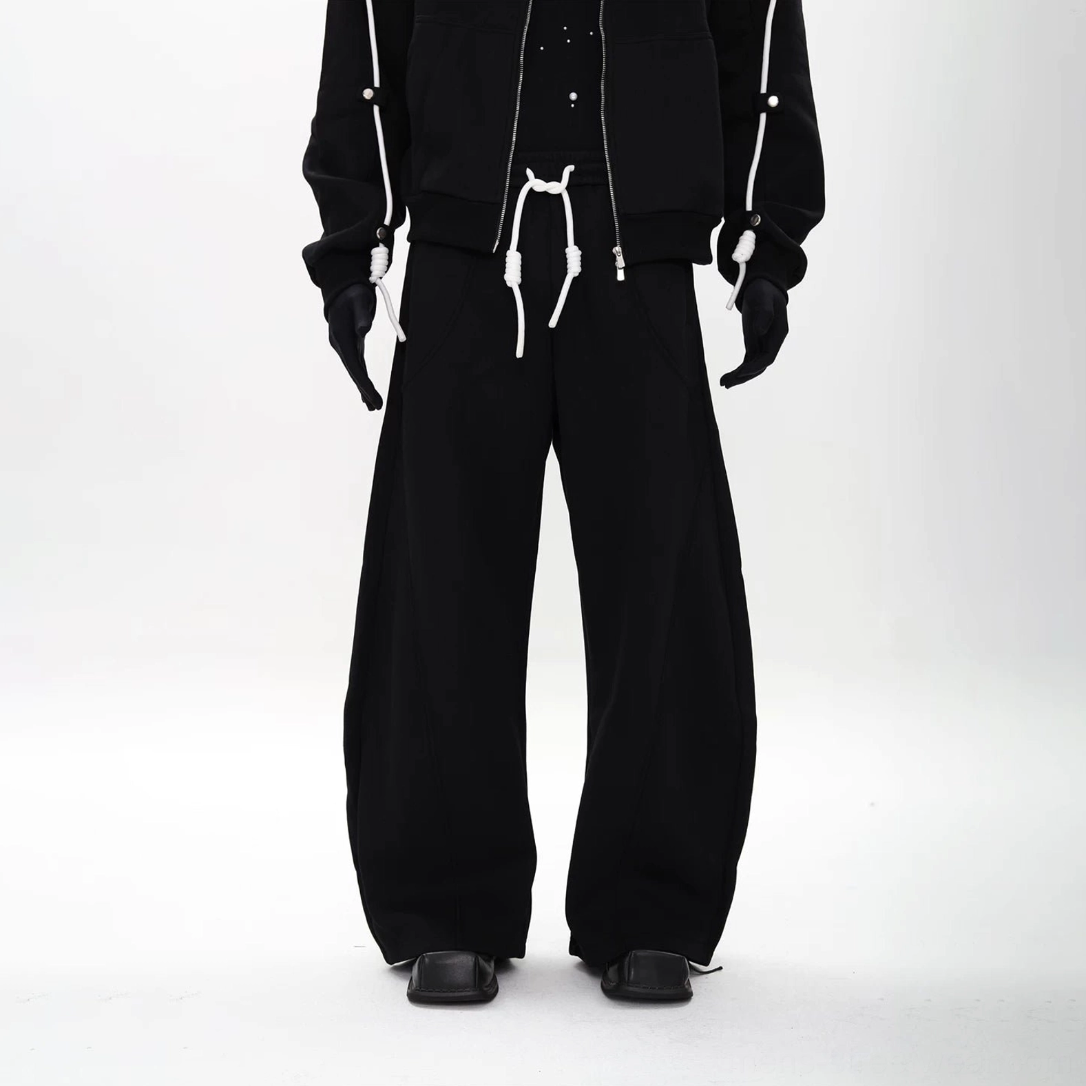 Black wide-leg sweatpants paired with modular hoodie, highlighting the loose draped silhouette and shoulder cord streetwear details