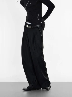 Side view of black wide-leg tailored streetwear trousers with fluid drape styled with a fitted black top and pointed leather shoes