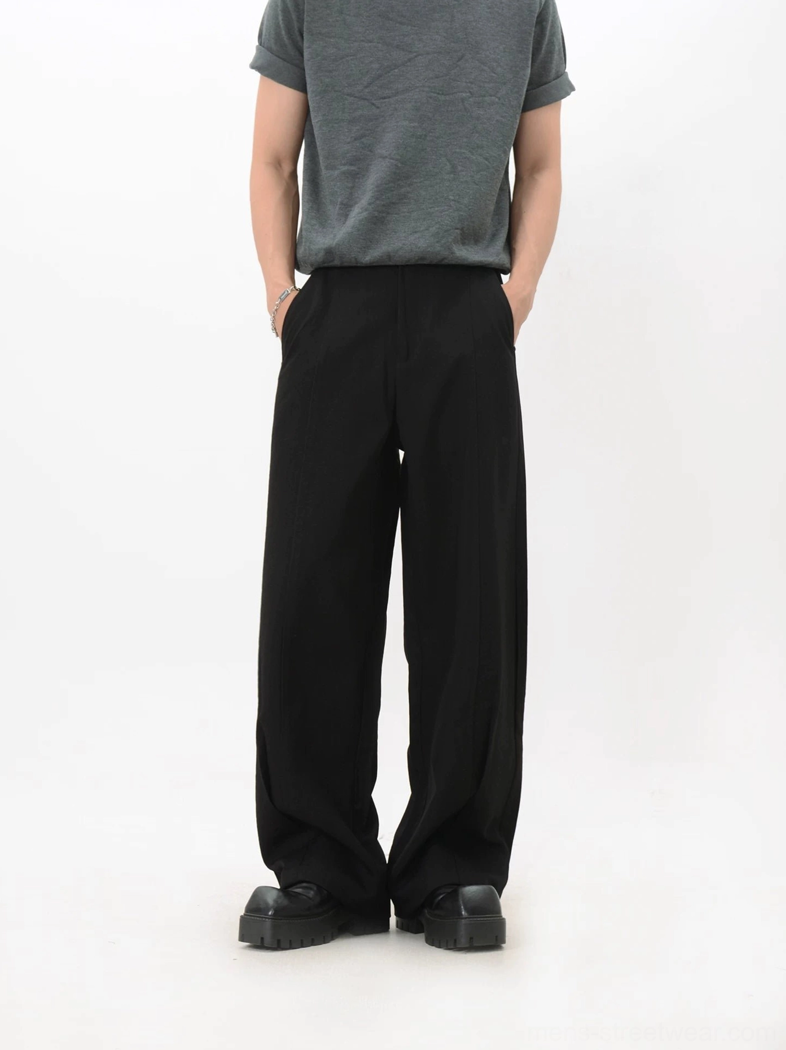 Black wide-leg tailored trousers displayed from the front with clean seams, deep side pockets, and a modern relaxed formal silhouette