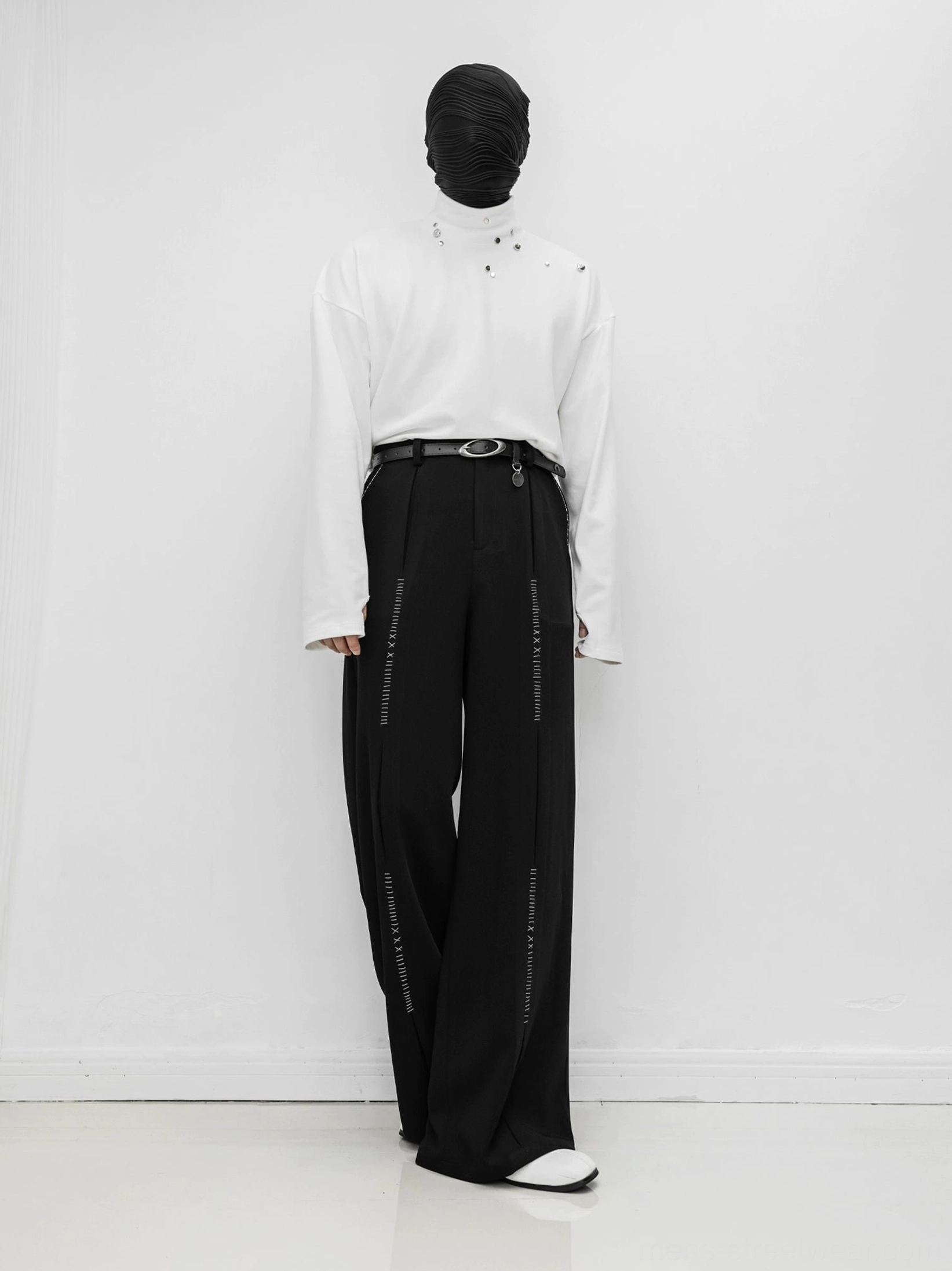 Black wide-leg tailored trousers in a full front view with neat pleats, smooth drape, elongated silhouette, and symmetrical leg stitch details