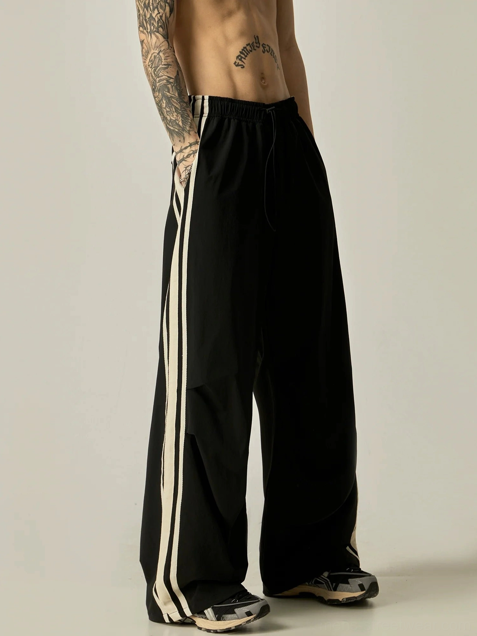 Black wide-leg triple stripe nylon track pants with off-white side stripes and adjustable drawstring waistband front view