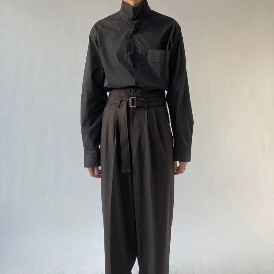 Black wide-leg trousers with detailed rectangular buckle belt and relaxed pleated fit styled with a black stand-collar shirt