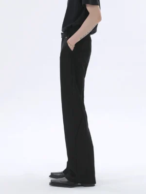 Side profile of black wide-leg trousers showing the tailored waistband, fluid suiting fabric, structured leg seams, and relaxed Korean streetwear silhouette