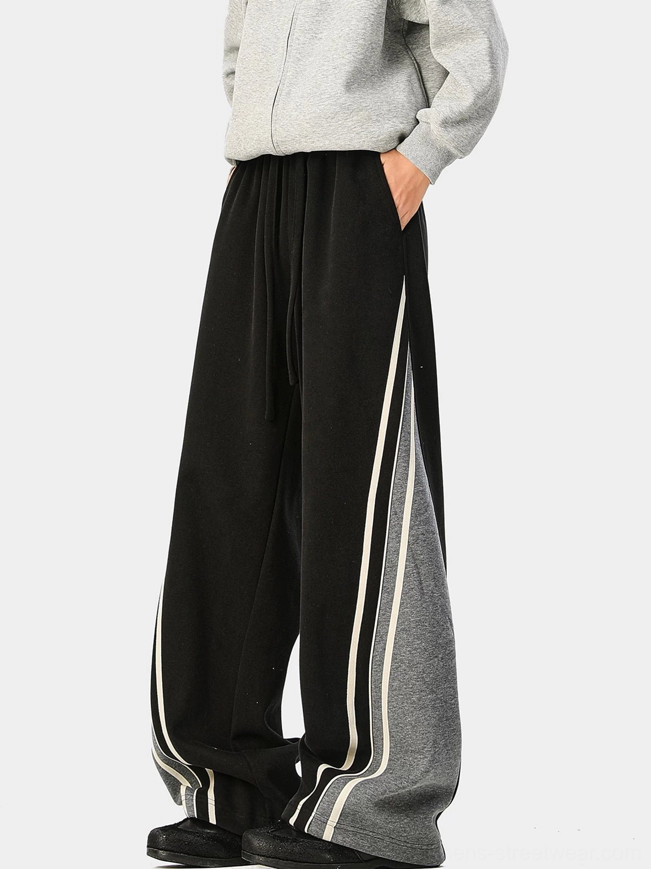 Black wide-leg varsity track pants with gray side panel, double off-white stripes, elastic drawstring waist, and relaxed fit