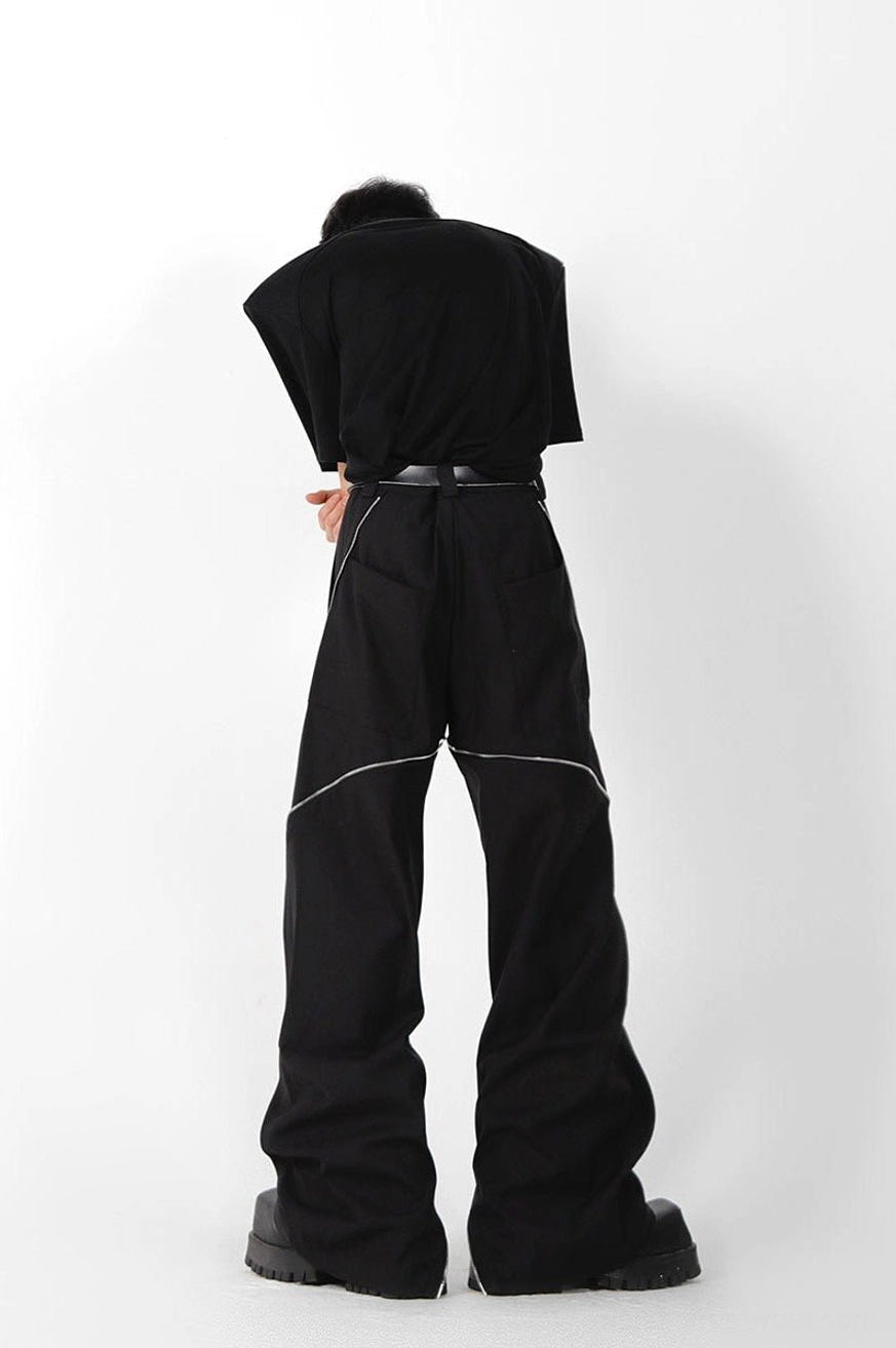 Rear view of black wide leg zipper trousers with outer rear-leg zipper seams, a simple waist belt, and modern unisex streetwear proportions