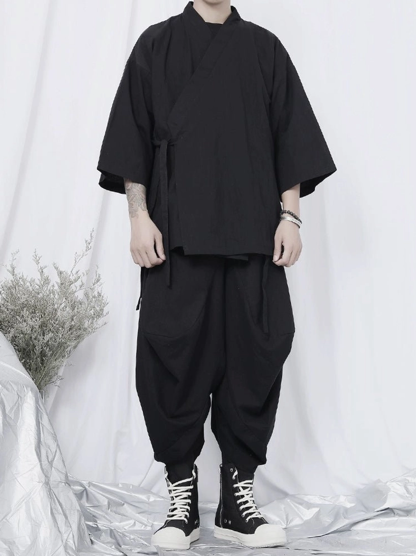 Black wrap kimono shirt with loose three-quarter sleeves styled with relaxed harem pants, side pockets, and monochrome streetwear accessories