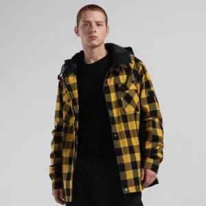 Black and yellow buffalo plaid hooded outdoor jacket styled with black trousers, button-front closure, chest flap pockets, and bold gorpcore streetwear appeal