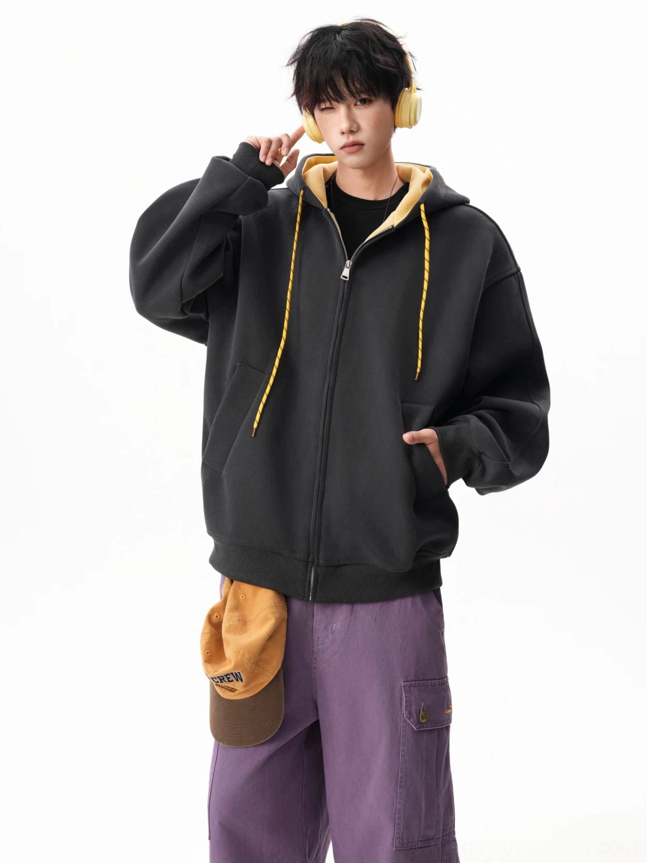 Black and yellow contrast oversized zip-up hoodie styled with purple cargo pants and yellow headphones