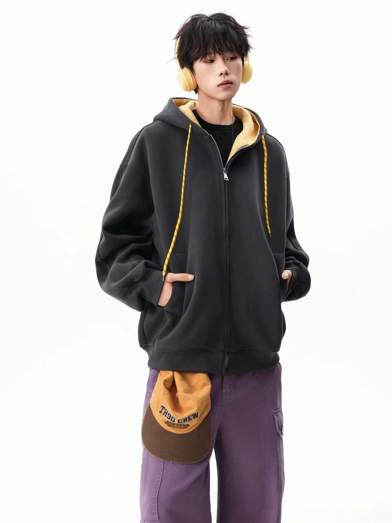 Three-quarter front view of a black and yellow contrast zip-up hoodie with front hand pockets and oversized fit