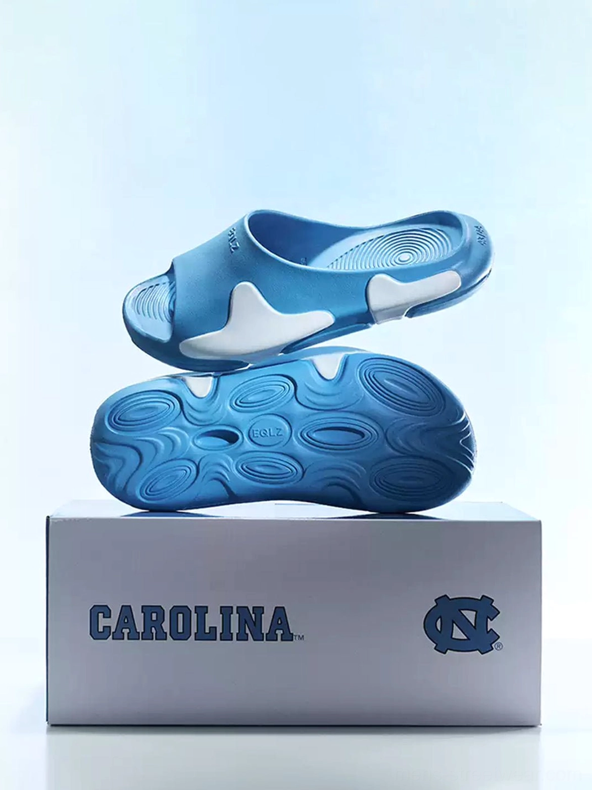Blue cloud-inspired open-toe slides displayed from above showing the two-tone upper and textured outsole