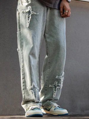 Model wearing blue and cream art inspired low-top skate sneakers with distressed patchwork denim in a casual streetwear outfit