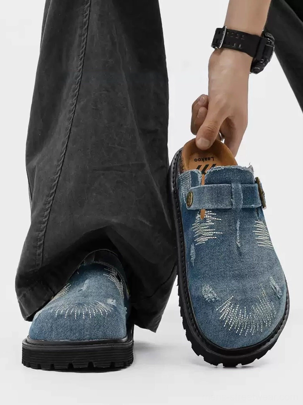 Blue distressed denim platform mule clogs styled with dark gray cargo pants, adjustable buckle strap and visible cork-style footbed