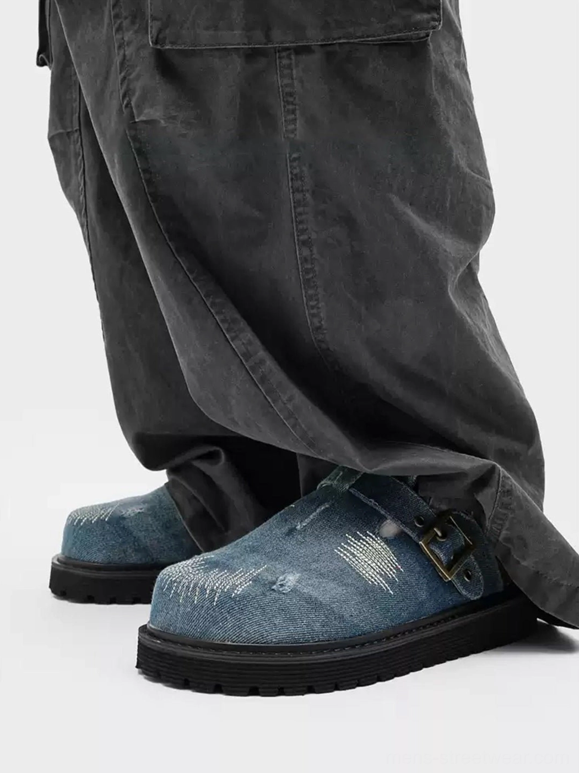 Pair of blue distressed denim platform clogs with chunky soles and adjustable buckle straps styled in a contemporary streetwear outfit