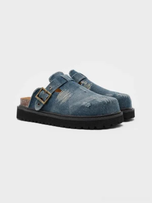 Blue distressed denim platform mule clogs with frayed texture, vintage buckle strap, cork-style footbed and chunky rubber sole on a white studio background
