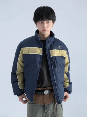 Blue and khaki color block boxy puffer jacket worn by male model in front view with stand collar and zip pockets