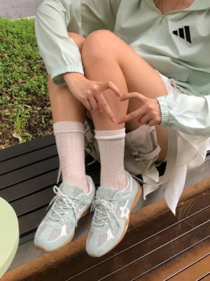 Blue mesh star German trainer sneakers worn with white crew socks and casual light sportswear in an outdoor streetwear setting