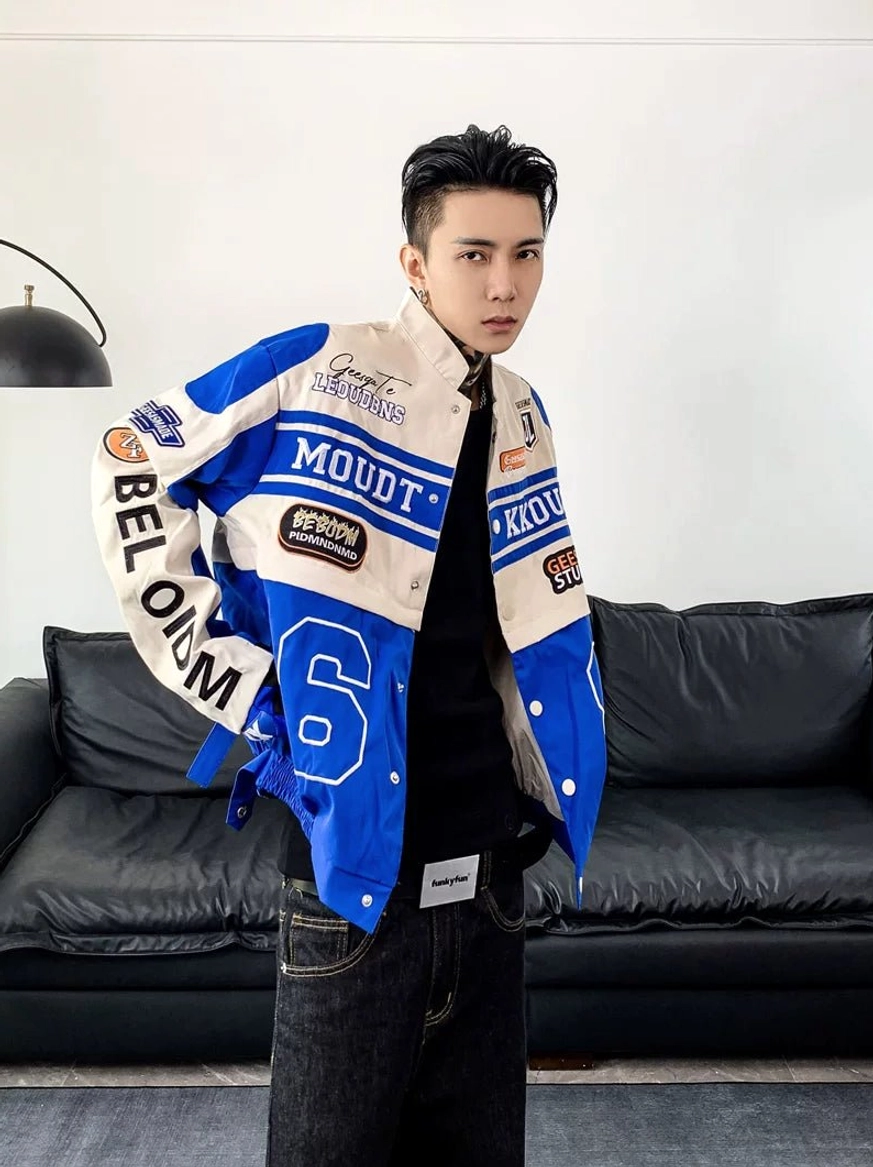 Front view of a blue and off-white motorcycle racing varsity jacket with sleeve patches, graphic number, black top, and dark denim