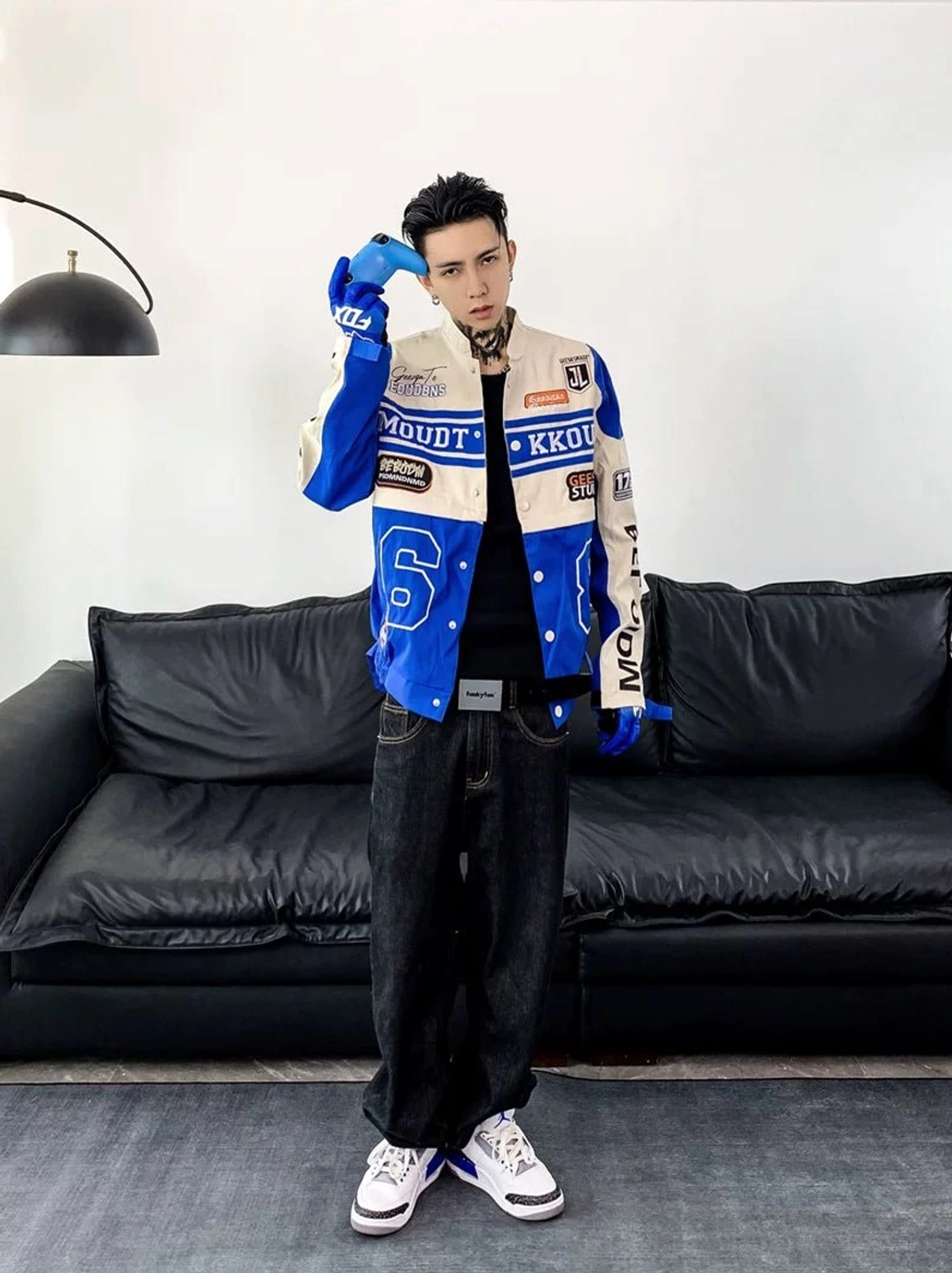 Blue and off-white motorcycle racing varsity jacket styled with blue racing gloves, dark jeans, and white casual sneakers