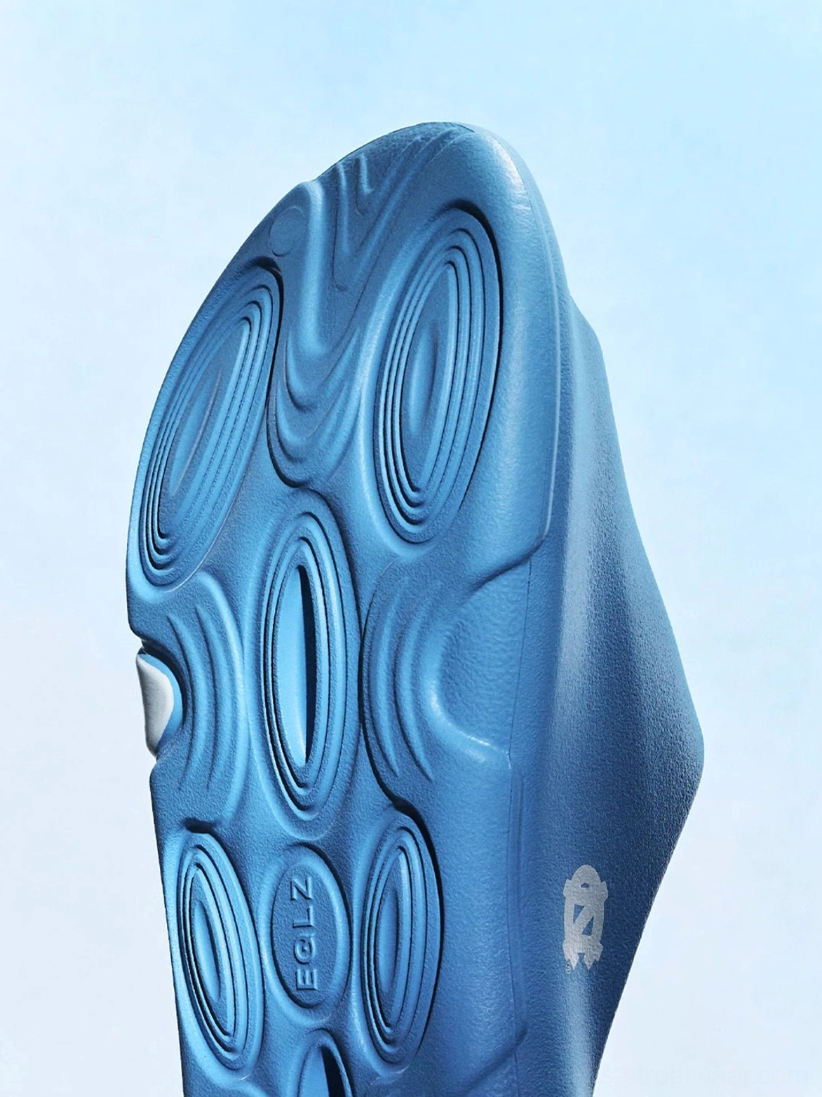 Close-up of the wave-patterned textured outsole on blue open-toe streetwear slides