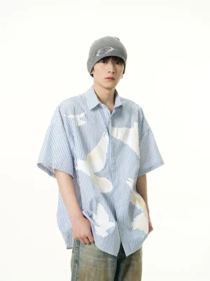 Blue pinstripe dove print oversized short sleeve button-up shirt front half-body view with gray beanie and washed denim