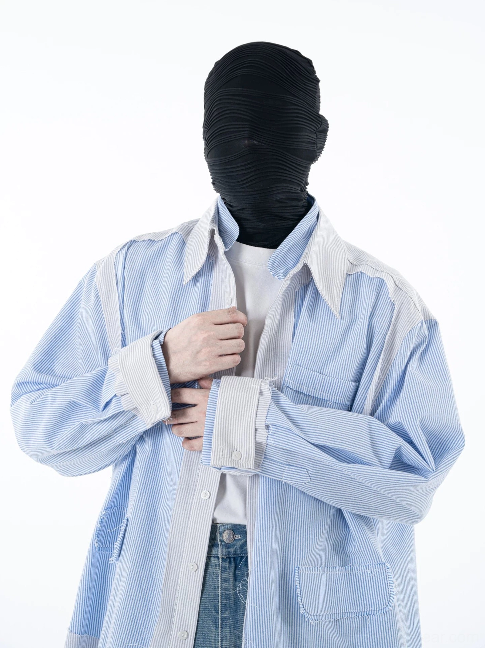 Front close-up of an oversized blue pinstripe overshirt showing contrast cuffs frayed patch pocket trim white tee layering and denim styling