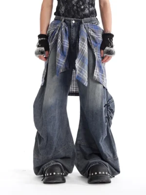 Front view of oversized blue plaid layered balloon jeans with wide legs, washed denim, tartan waist panel, and punk streetwear styling