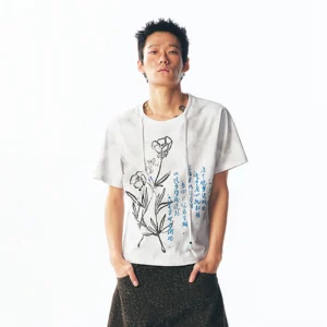 Front full-body view of a blue script floral graphic cotton tee with black hand-drawn flowers and blue Chinese calligraphy styled with dark wide-leg streetwear pants