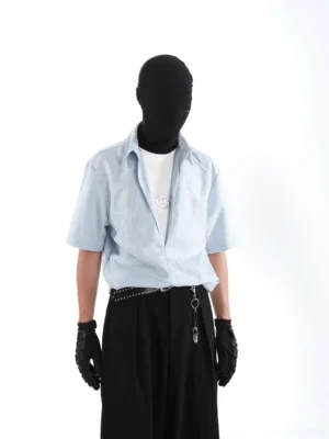 Front view of a light blue vertical striped layered streetwear shirt styled with black wide-leg trousers, gloves, and a metal chain belt