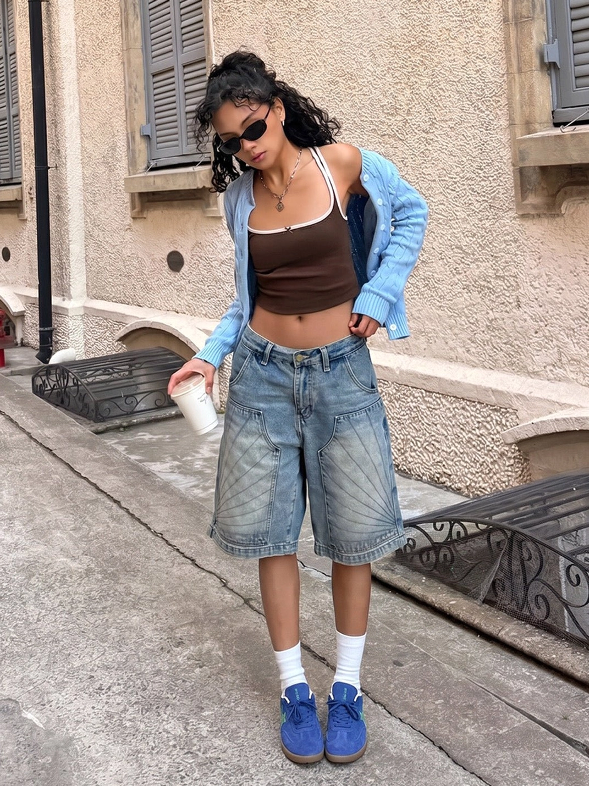 Blue suede gum sole trainers styled with a retro cardigan and denim shorts in a full body outdoor Korean fashion streetwear look