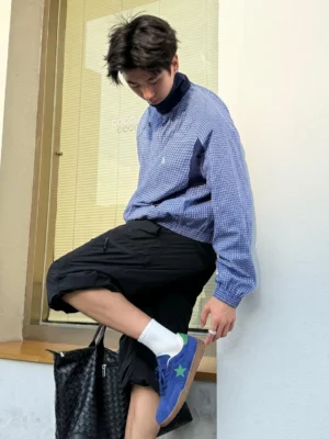 Blue suede star trainers worn by an Asian male model with white crew socks, blue checkered pullover, and black cargo shorts in a Seoul inspired streetwear setting