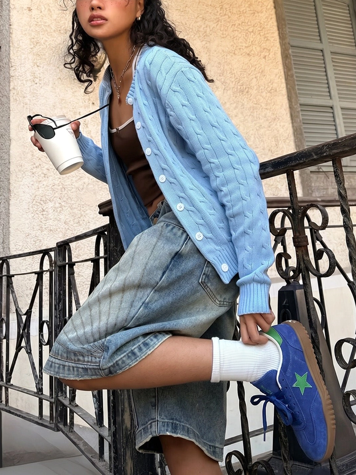 Blue suede star embroidered trainers worn with white socks, denim bermuda shorts, brown crop top, and light blue cardigan in a vintage streetwear outfit
