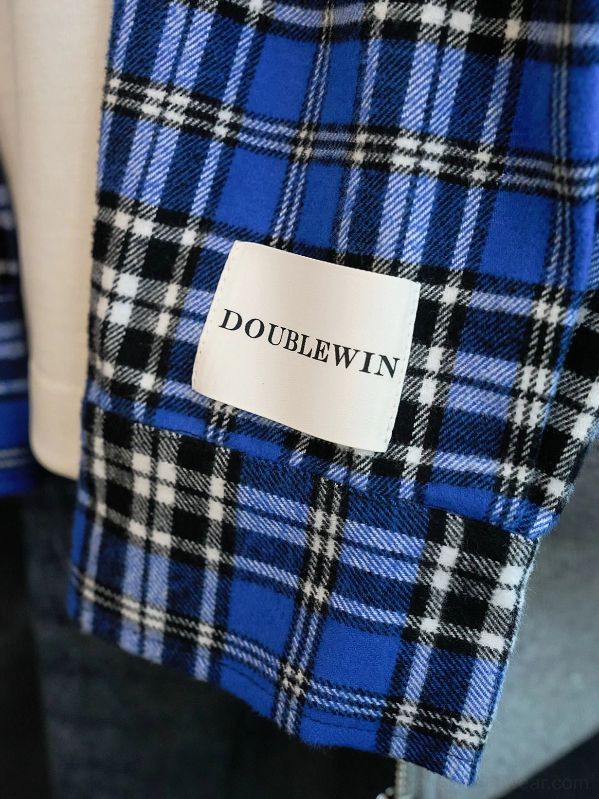 Close-up view of the blue black and white tartan plaid cotton lining inside a gray oversized zip-up hoodie