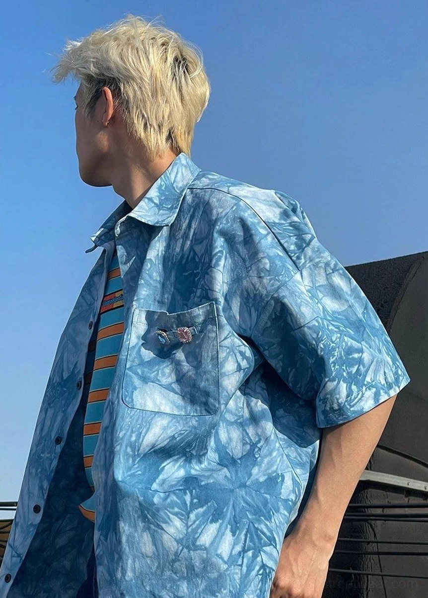 Side view of a loose blue tie-dye short sleeve shirt styled with a striped inner T-shirt for summer streetwear