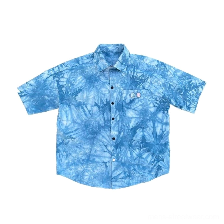 Flat lay view of a blue tie-dye short sleeve button-up shirt with chest pocket and relaxed streetwear fit