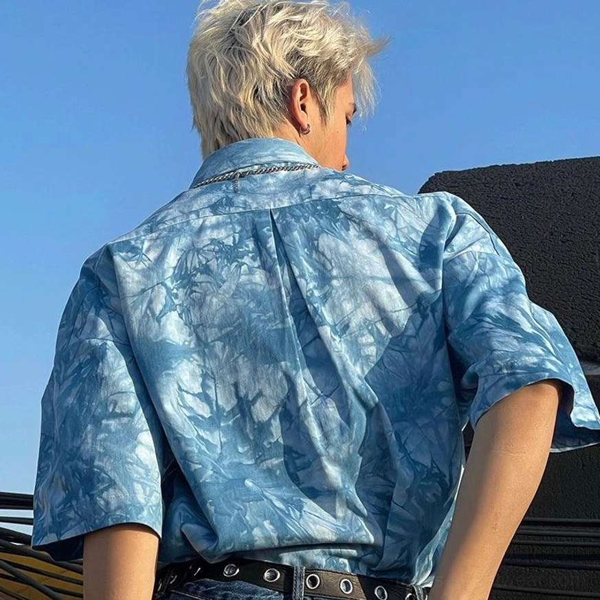 Rear three-quarter view showing the blue tie-dye short sleeve shirt back pleat and relaxed oversized silhouette