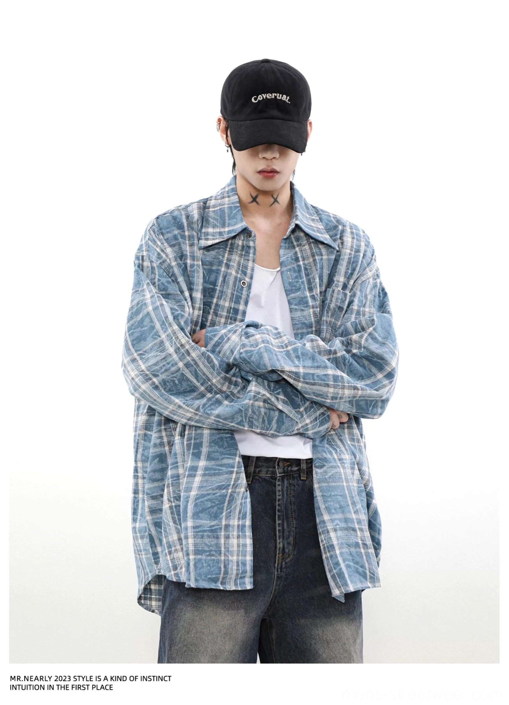 Model wearing a blue washed plaid long sleeve overshirt with relaxed oversized fit and casual layered streetwear styling