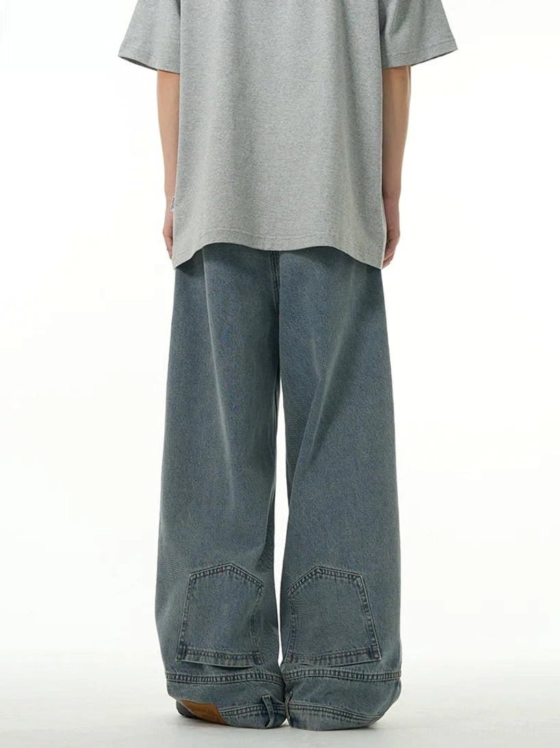 Back view of blue relaxed wide-leg denim jeans featuring square lower-leg patch pockets and loose straight construction