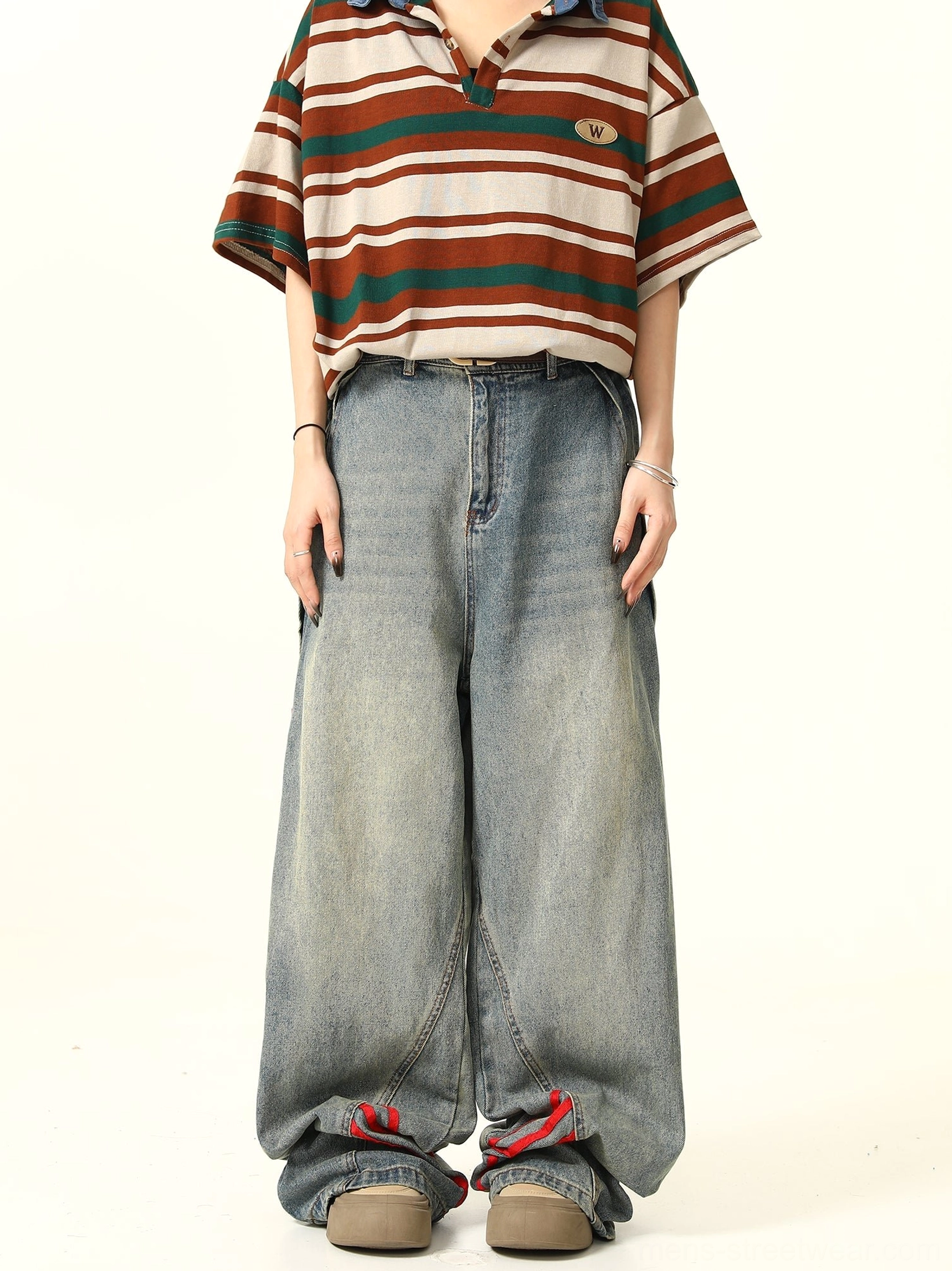 Front full-body view of blue wide-leg denim jeans with bold red triple-stripe details at the outer leg seams, styled with a striped polo shirt and casual shoes