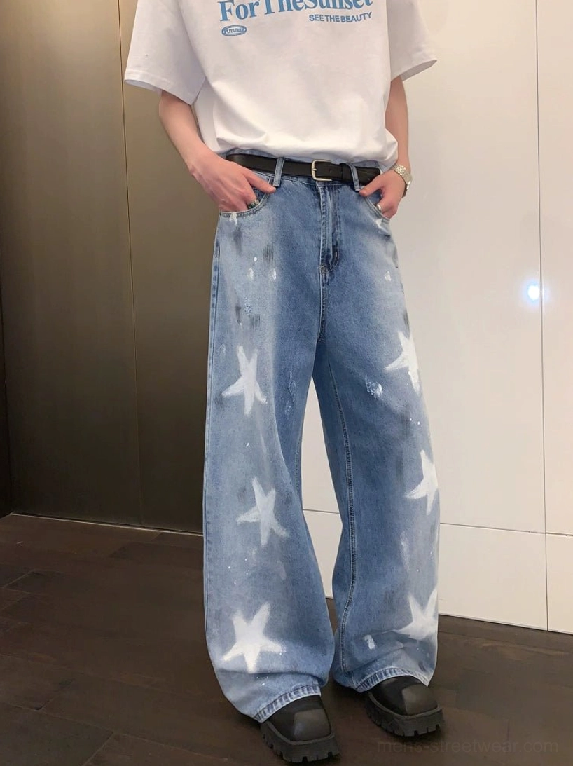 Three-quarter view of relaxed blue star print wide-leg jeans with faded wash and paint splatter details in Korean streetwear styling