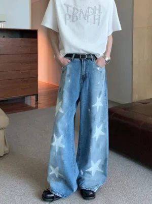 Male model wearing blue wide-leg star print washed denim jeans with white graphic stars in a streetwear outfit front view