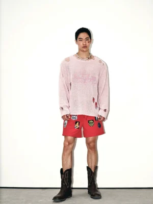 Front view of a blush pink distressed oversized knit sweater with cursive chest embroidery, extra-long sleeves, and a relaxed grunge streetwear fit