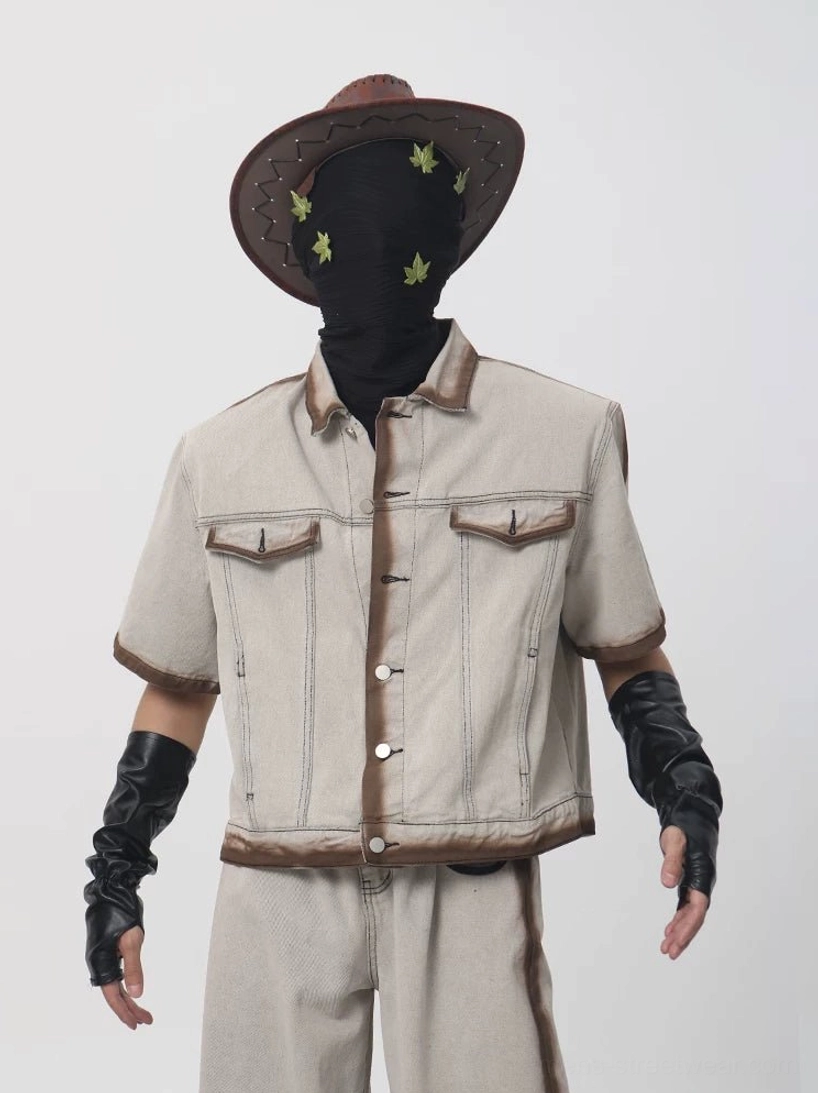 Front close up of a boxy cropped short sleeve denim jacket with brown burnished edging button placket and dual chest flap pockets