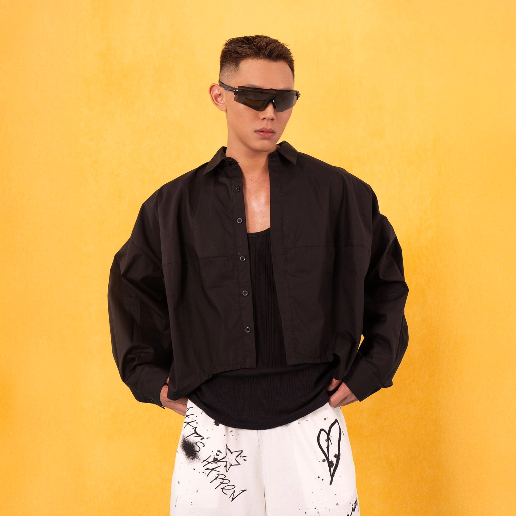 Black oversized cropped poplin button-up shirt layered over a black tank top in minimalist Seoul streetwear styling