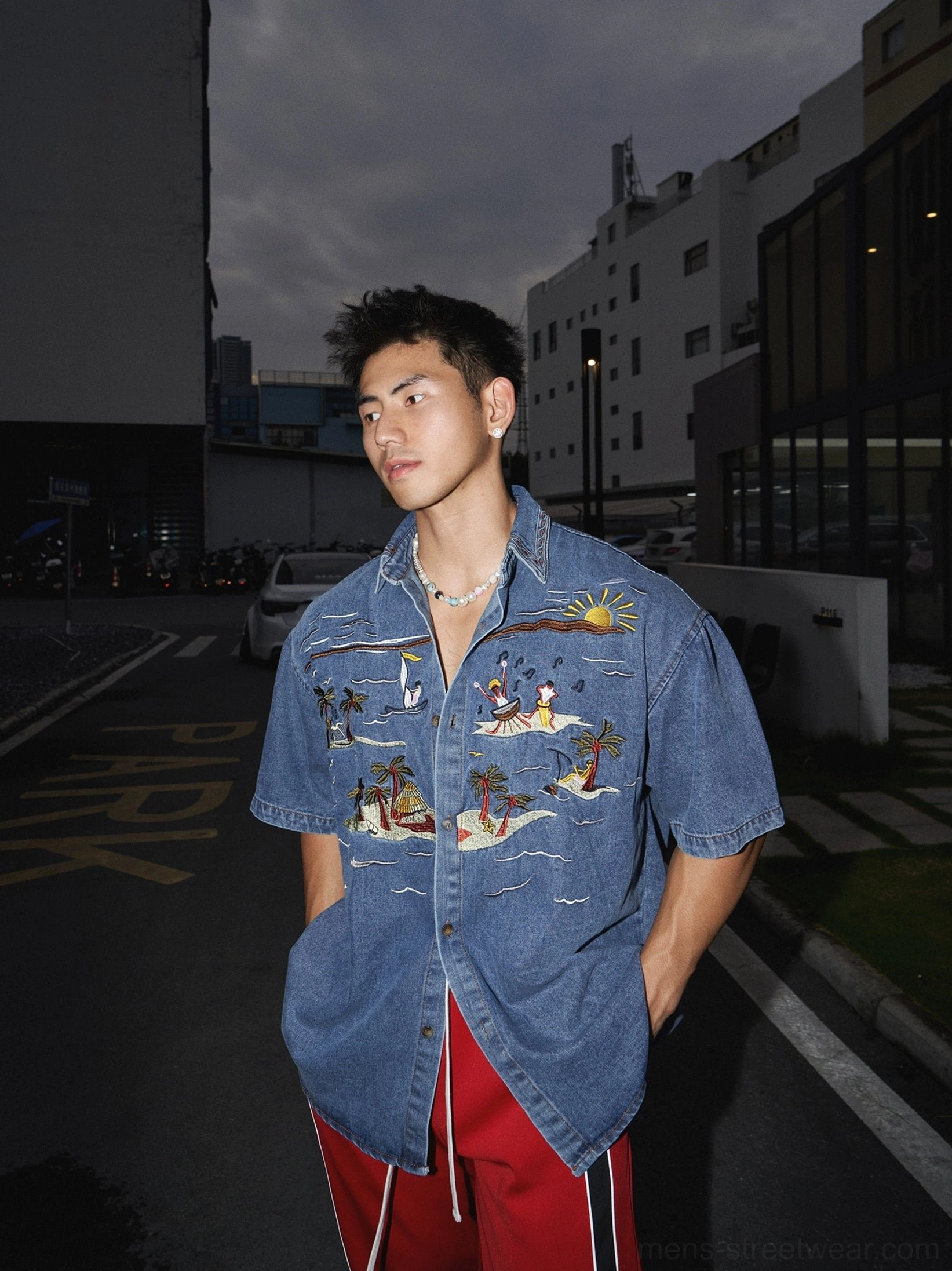 Boxy oversized tropical embroidered denim shirt styled with red stripe track pants in contemporary streetwear fashion