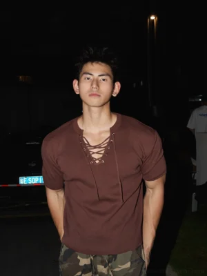 Brick Red lace-up ribbed slim-fit T-shirt with crisscross neckline styled with camouflage cargo pants in an urban night streetwear setting