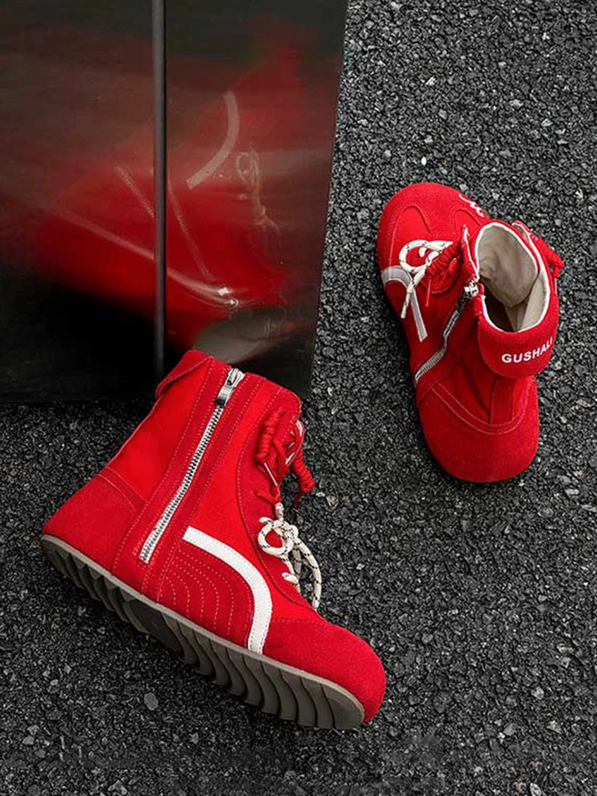 Bright red high-top suede racing training boots with white contrast stripe, double laces, and side zipper on asphalt