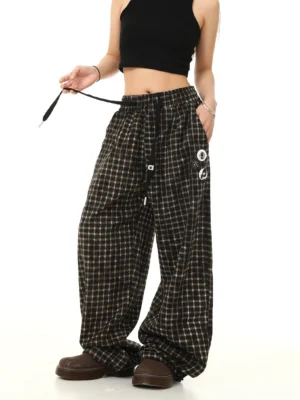 Three-quarter view of oversized gingham wide leg track pants showing elastic drawstring waist and functional side pockets