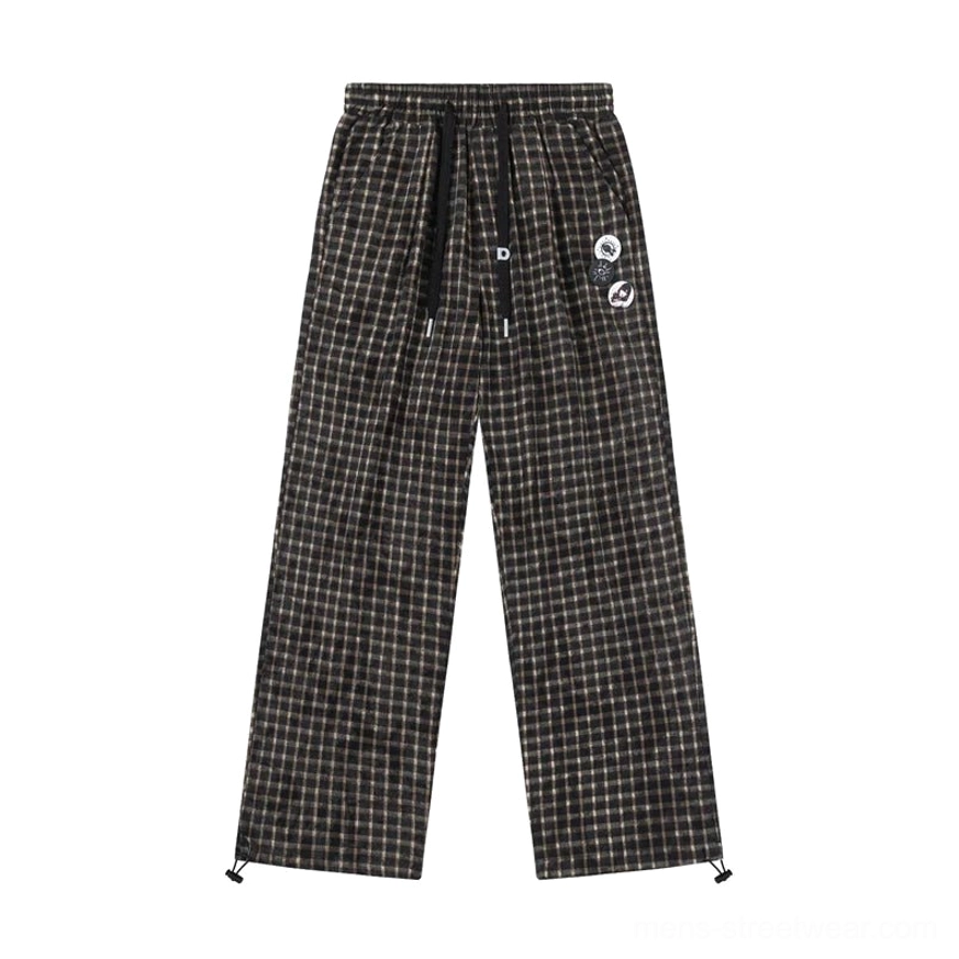 Flat lay of brown black gingham wide leg track pants with drawstring closure side pockets leg badges and adjustable hem details