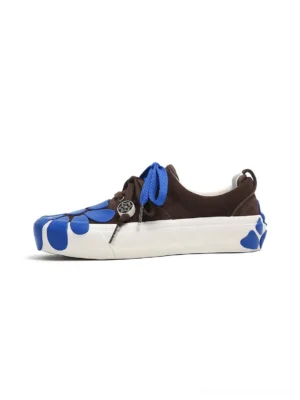 Left side view of brown suede platform sneakers with blue daisy details, double blue laces, metal lace charm, and thick white rubber sole