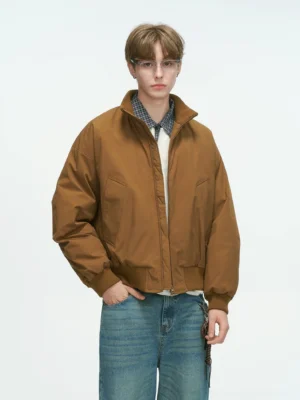 Tan brown bomber jacket with clean solid woven fabric texture, full front body shot showing stand collar and relaxed fit on model with blue jeans